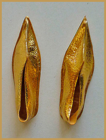 Metallic gold shoes in a leather-like material with long pointed toes that curl up a bit near the tip