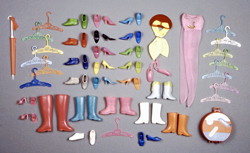The "pieces" from the 64-piece shoe bag are laid out. The reader is referred to Blitman's book for the full description, but I will note the pictured set includes ten pairs of closed-toed pumps (in acid green,, aqua, black, blue, hot pink, lime green, orange, raspberry, royal blue, and yellow), two pairs or open-toed pumps, one pair each of ballet flats, sneakers, and bow shoes, four pairs of ankle boots, and six other pairs of boots of varying height, including the majorette boots introduced in '64. Other pieces include luggage, tights, hangers, and more. 