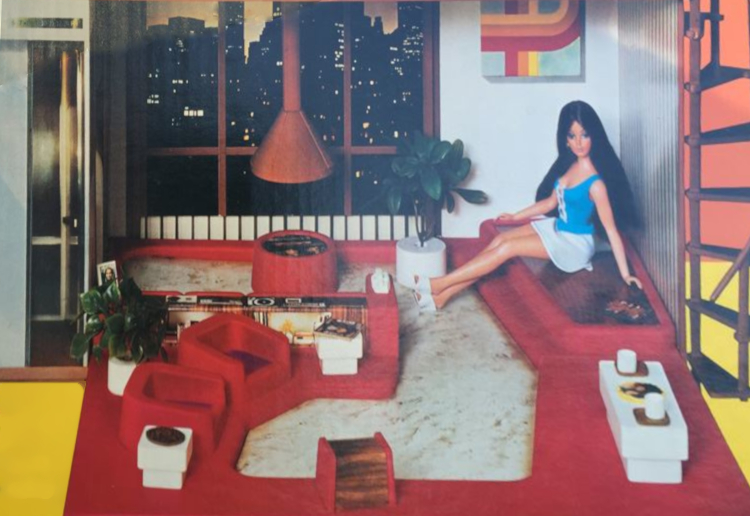 Same as the shot of Tuesday Taylor in her apartment used at the top of the post, but Tuesday's blonde hair has been flipped around to brunette. This shot has a wider frame including more of the seating in the foreground with potted plant, several small tables, and at the very edge the spiral staircase going up the exterior of the structure.