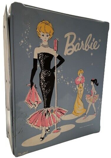 Carrying case illustrated with blonde bubblecut wearing Solo in the Spotlight, standing at a mic and holding her handkerchief. The mic, handkerchief, and flounce are all in pink. Color inventiveness was routine in carrying cases, and in the background of this one we also see Enchanted Evening in gold with pink stole, plus Ballerina in standard pink.