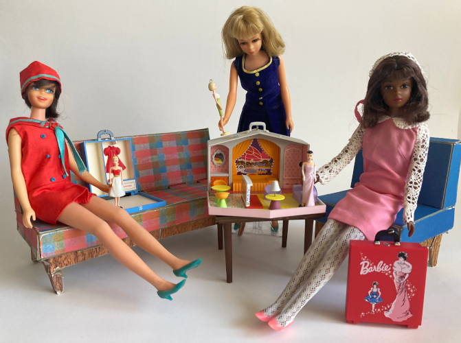 A square wooden table holds a mini case room lying open with its interior displayed. The interior consists of colorful, modern-style molded plastic furniture anchored in place on screened floors and walls. Francie stands behind the table, holding a miniature American Girl Barbie just over the top of the mini house. Casey sits on the sofa, at left, holding a mini blonde ponytail Barbie in Silken Flame in front of a mini case with Red Flare sculpted onto the back as if hung. At right, A second Francie (in Dance Party) sits on a blue chair and holds a mini brunette ponytail Barbie in Enchanted Evening in the mini house's living room. At her feet is a closed mini carrying case illustrated with a bubble cut brunette Barbie in Enchanted Evening--and a smaller one wearing Friday Nite Date in the background, surrounded by a starry trail and the Barbie logo on red background.