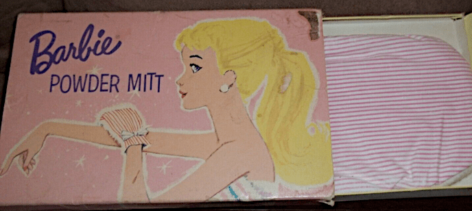 Powder Mitt package, partially open to show the pink-and-white striped mitt. On the pink box is a drawing of blonde pontyail Barbie in profile, wearing the mitt on one hand and applying it to her other arm. She appears to be wrapped in a towel--mostly only her head and shoulders are in view--and wears large pearl earrings. Little sparkles of white dance around her arm and mitt. The words POWDER MITT, like the words BEAUTY KIT in the previous image, are made up of letters with slight vertical shifts relative to one another.