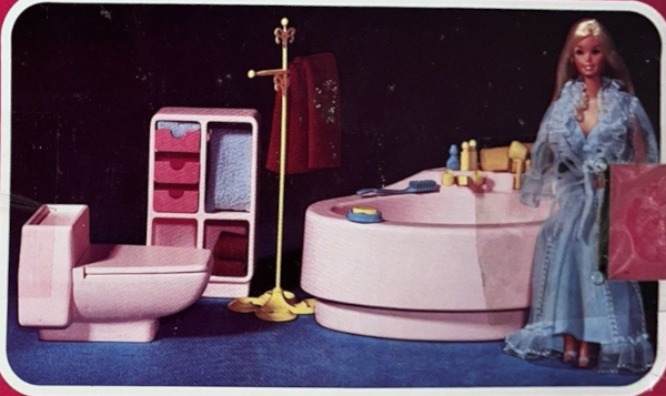 Color photograph from package for 1979 Dream Furniture bath chest and commode, showing the commode and a spa bathbut in pale pink plastic, a set of shelves/drawers in pale pink with hot pink accents, a towel rack, and blonde Superstar Barbie in a baby blue negligee perched on the tub edge.