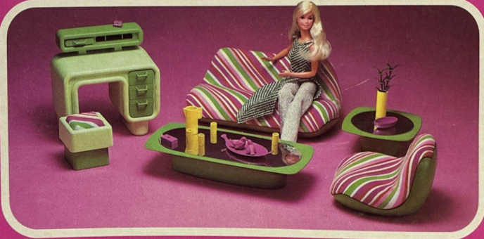 Product image from Dream Furniture packaging. On a pink background, blonde Superstar Barbie sits on a blobular sofa striped in white, green, and pink diagonals. A similar chair sits of one side. An end talbe and coffee table in green plastic have mirrored tops. To one side is a desk in molded light green plastic with dark green accents, along with a molded plastic green stool with the same diagonal stripe for a seat cover. The molded plastic curves instead of having abrupt corners.