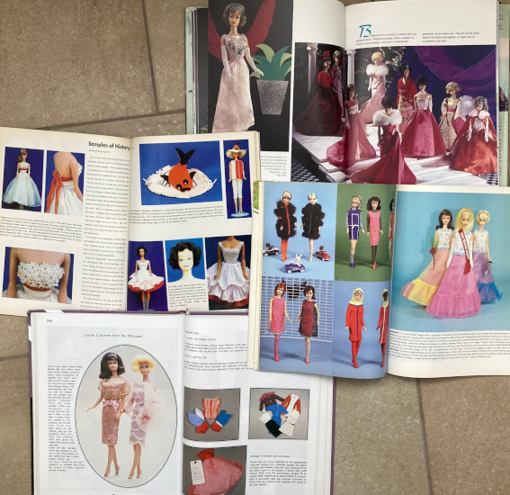 Four books/magazines lie open on a tile floor. The top book's pages are dominated by big color photos of Barbie dolls, including bubble cut and side part American GIrls, in pink and red gowns. These include Enchanted Evening in a darker berry color, Midnight Blue in red, and some that aren't recognizable from US market fashions. Middle row is two magazine spreads. One page shows Barbie in a white ballcown with flower applique bodice and orange or red sash belt; one is a Bermuda shorts outfit with white shorts, a sleeveless blouse in half white, half orange, and a wild straw hat with silly-looknig fish ornament, as well as Midge in a fit-and-flare dress, white, with handkerchief square bottom hem and red or orange underskirt; and the second magazine displays five images of Francie or Casey, in each one the doll wears a known fashion in its known color scheme and then one or two other dolls are dressed in color variants, including Swingin' Skimmy with white trim and Silver Cage with a black "cage." Finally, a book open to show two American Girls--one a side part--in pink knee-length dresses that were never marketed in the US; the other page shows fashions lying flat, including swimsuits and shift dresses, and one Maginificence that looks like the produced gown but has a production sample tag.